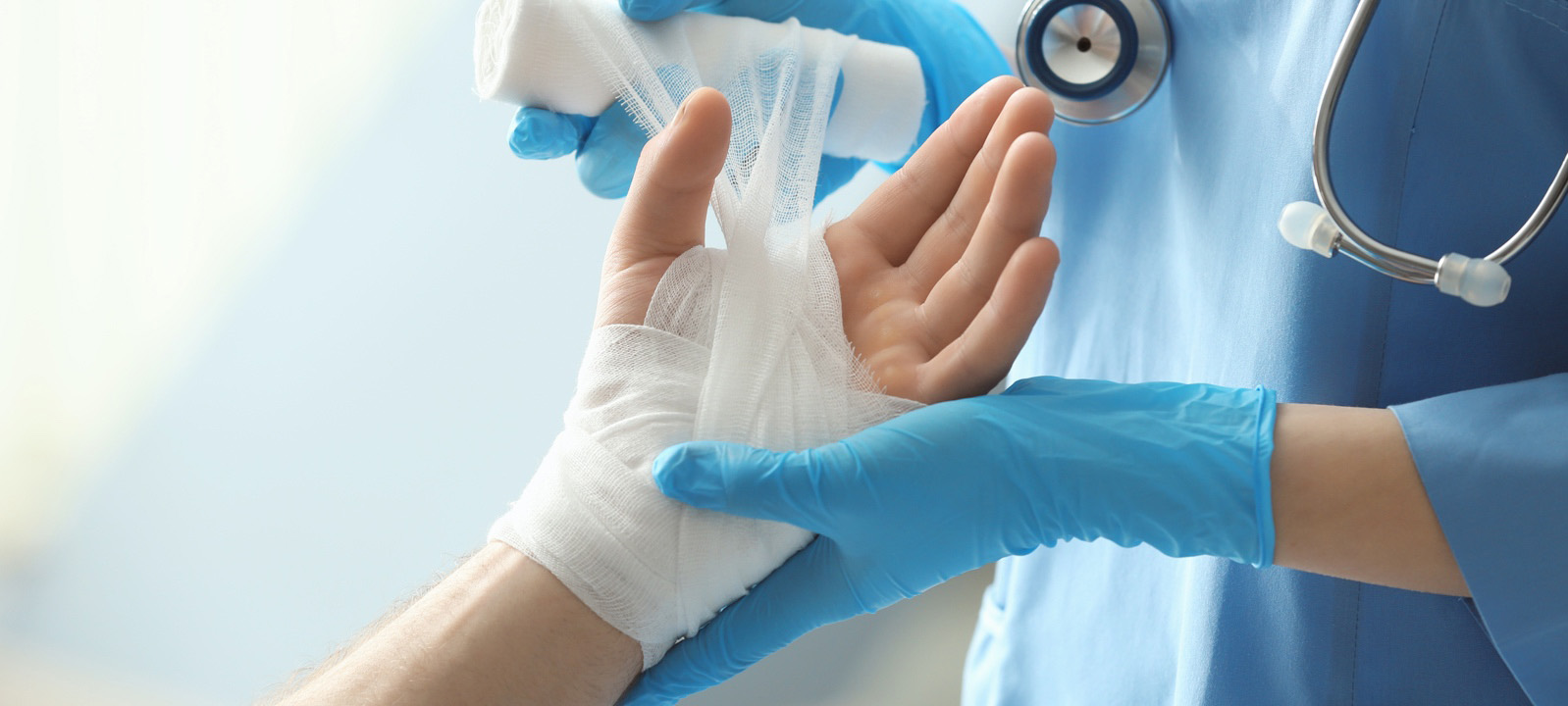 A medical professional wrapping a bandage around a patient's hand